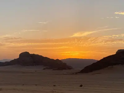 a sunset in the desert with mountains in the background at Fig Tree Eco Camp in Disah