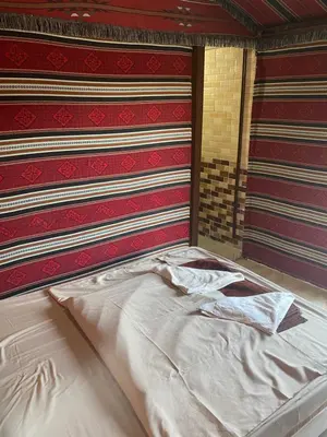 an empty bed in a room with red andkered walls at Fig Tree Eco Camp in Disah