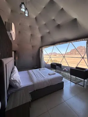 a bedroom with a large bed and a large window at Alkaram luxury camp in Wadi Rum
