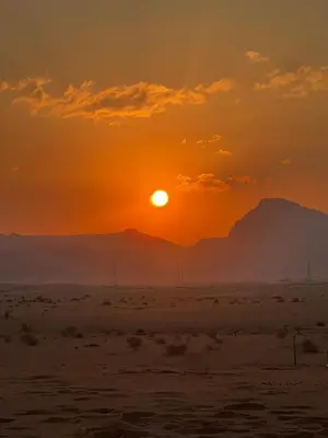 a sunset over the desert with mountains in the background at Alkaram luxury camp in Wadi Rum