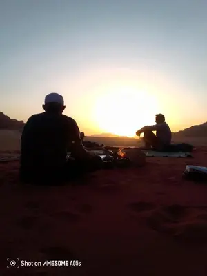 two people sitting in the desert watching the sunset at Ragheb Al-Zawaida in Disah