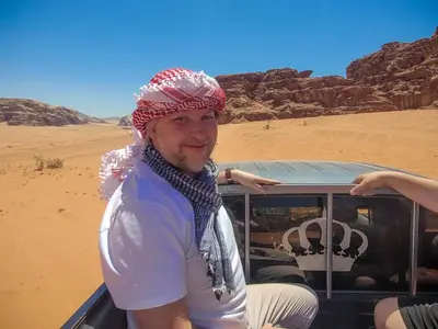 a man wearing a headdress standing in a truck in the desert at Bedouin house in Wadi Rum