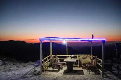 a table and chairs under a blue canopy at sunset at Wadi Ghowair View Camp in Al Khuraybah