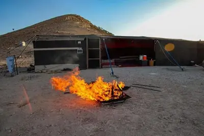 a fire is burning in front of a building at Wadi Ghowair View Camp in Al Khuraybah
