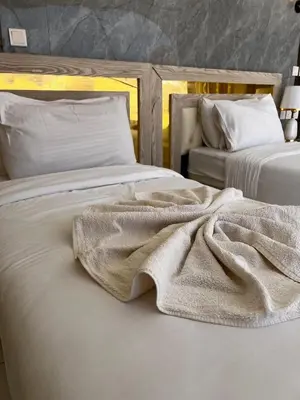 two beds with white sheets and a blanket on them at The Flowers Camp in Wadi Rum