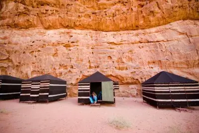 a person sitting in a tent in front of a cliff at مخيم وهج رم in Disah