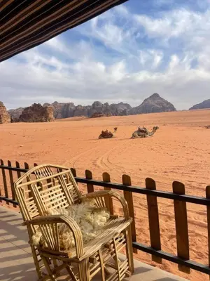 a wicker chair sitting on a porch in the desert at مخيم وهج رم in Disah