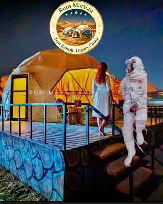 a man and a woman standing on a pier next to a tent at RUM MARTIAN TENT BUBBLES lUXURY CAMP in Wadi Rum