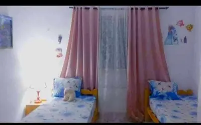 a bedroom with two twin beds and curtains at Loard House in Az Zarqa