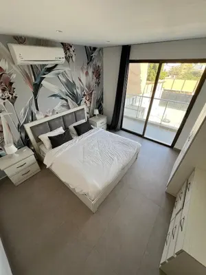 a bedroom with a white bed with a floral wall at Eva chalet in Deadsea in Al Kafrayn