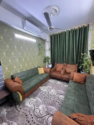 a living room with a green couch and chairs at Rawabi INN in Maţār al Malik Ḩusayn