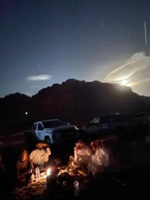 a group of people sitting around a fire at night at The heartbeat of the desert and the stars in Wadi Rum