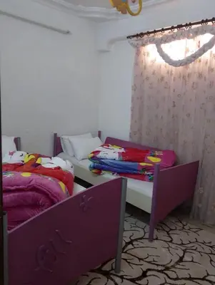 a bedroom with two beds and a window with curtains at Coazmatic apartment in Kerak
