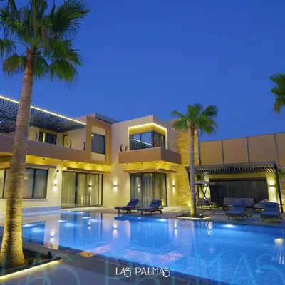 a swimming pool in front of a house with palm trees at Las palmas resort in Sowayma