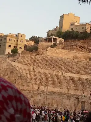 a crowd of people standing in front of an amphitheater at over theatre apartment in Amman