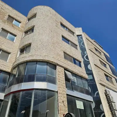 a tall brick building with glass windows at Cozy apartment in Amman
