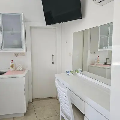 a white bathroom with a sink and a mirror at Cozy apartment in Amman