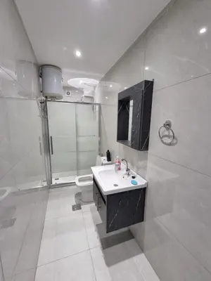 a white bathroom with a sink and a shower at Sama Dier Ghbar 1 in Amman