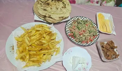 a table topped with plates of food and french fries at Zarmot INN in Az Zarqa