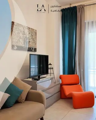 a living room with a tv and a couch and a chair at Al RAHA village - Aqaba أستوديو بقرية الراحه العقبة مرسى زايد in Aqaba
