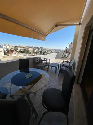 a balcony with a table and chairs and a view at abdoun rooftop 1bedroom kh&sh 04 in Amman