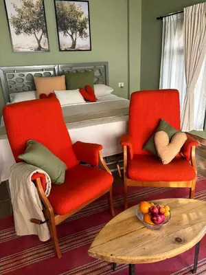 a bedroom with a bed and two chairs and a table at Olive house in Um Qeis