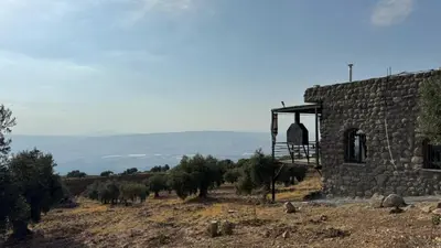 a stone building on top of a hill with trees at Olive house in Um Qeis