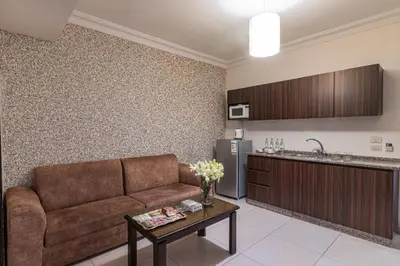a living room with a couch and a kitchen at Lancaster Hotel Apartments-Gardens in Amman