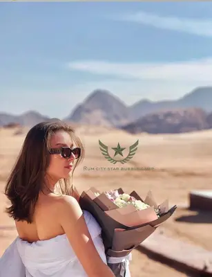 a woman holding a box of flowers in the desert at RUM CITY STAR BUBBLE lUXURY CAMP in Wadi Rum
