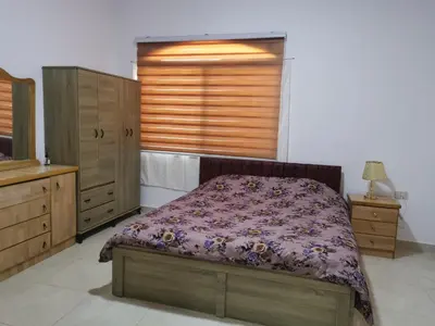 a bedroom with a bed and wooden cabinets and a window at zragat hotel in Jerash
