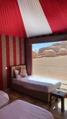 a bedroom with two beds and a large window at Amin Camp in Wadi Rum