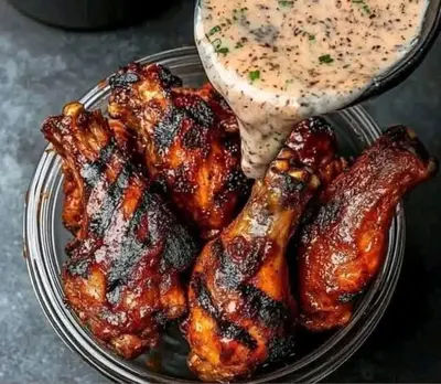a plate of food with chicken wings and a sauce at jarmy house in Ash Shajarah