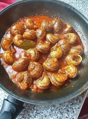 a pan filled with shrimp in a sauce at المنشيه ان in Al Manshīyah