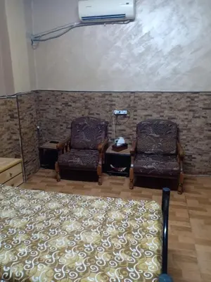 a bedroom with two chairs and a bed and a fan at الدونق in Amman