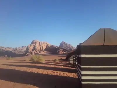 a building in the desert with mountains in the background at Wadi Rum 5-hour tour with sunset or morning, overnight stay with two meals and a Bedouin tent with a private bathroom Prices are for two people in Wadi Rum