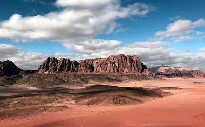 a view of a desert with a large rock formation at Wadi Rum 5-hour tour with sunset or morning, overnight stay with two meals and a Bedouin tent with a private bathroom Prices are for two people in Wadi Rum