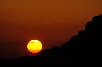 an orange sunset with the sun in the sky at Wadi Rum 5-hour tour with sunset or morning, overnight stay with two meals and a Bedouin tent with a private bathroom Prices are for two people in Wadi Rum