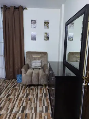 a room with a chair and a dresser and a mirror at New zarqa20 km from Amman in Az Zarqa