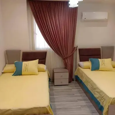 a bedroom with two beds and a window with curtains at دبه حانوت هاوس in Raʼs an Naqb