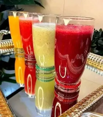 three glasses filled with different colored drinks on a table at Cool apartment in Maḩaţţat al Jufūr