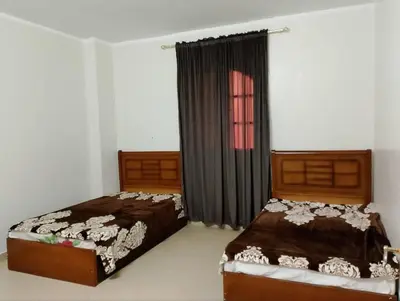 a bedroom with two beds and a window at Cool apartment in Maḩaţţat al Jufūr