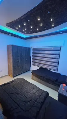 a bedroom with two beds and a window with aigunigunigunigun at Al Tamimi Furnished Apartments in Amman