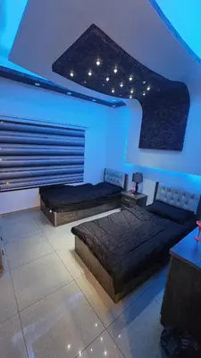 two beds in a room with blue lighting at Al Tamimi Furnished Apartments in Amman