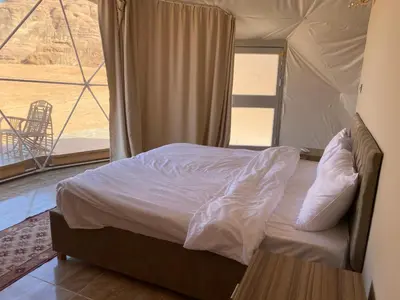 a bedroom with a bed in a tent with a view at Al Jawhara Luxury Camp in Wadi Rum