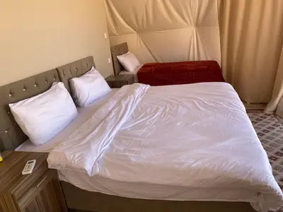 a bedroom with a bed with white sheets and pillows at Al Jawhara Luxury Camp in Wadi Rum