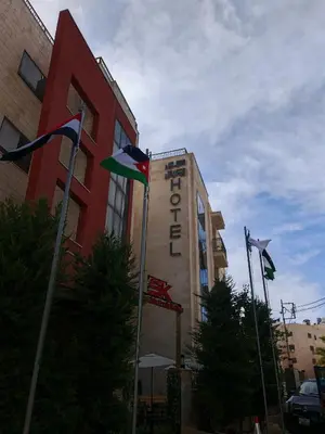 a building with flags in front of it at سهول الكرمل للأجنحة والشقق الفندقية in Amman