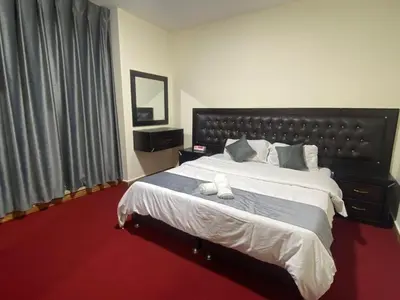 a bedroom with a large bed and a red carpet at سهول الكرمل للأجنحة والشقق الفندقية in Amman