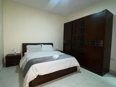 a bedroom with a large bed and a large wooden cabinet at سهول الكرمل للأجنحة والشقق الفندقية in Amman