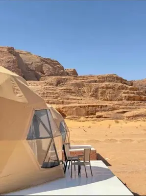 a tent with two chairs and a table in the desert at Aethera Sky Retreat Wadi Rum in Wadi Rum