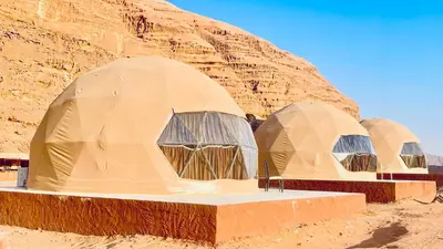 three domes in the desert with a mountain in the background at Aethera Sky Retreat Wadi Rum in Wadi Rum